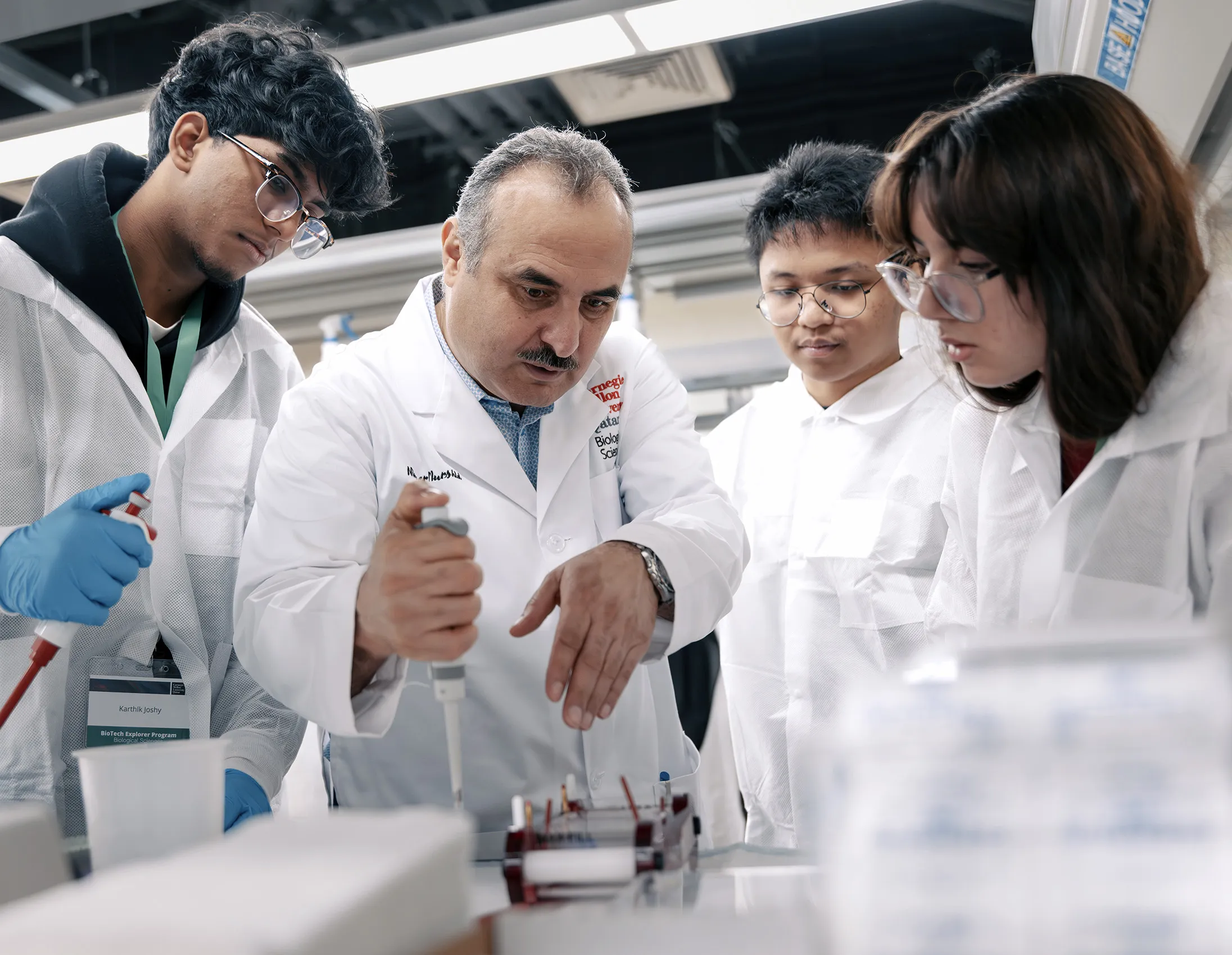 CMUQ Bio Sci faculty with students in the lab, demonstrating experiment